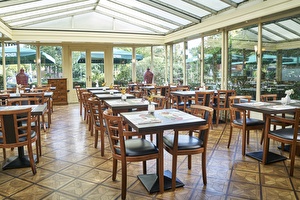 Amrâth Hotel Lapershoek Arenapark conservatory in restaurant Vivaldi, wooden tables set for breakfast with wooden chairs featuring a black soft seat.