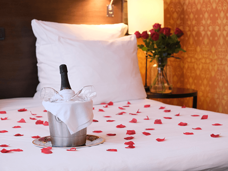 On a bed lies a bottle of champagne next to a bucket, perfect for a luxurious moment.