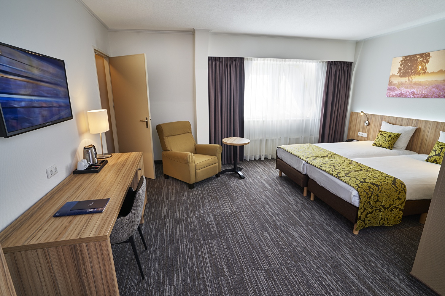 A spacious hotel room with two beds and a desk, furnished for comfort and functionality.