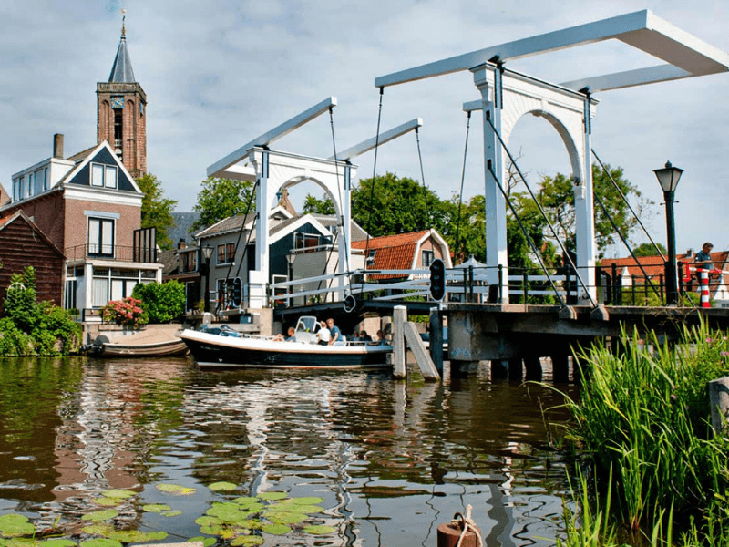 Een brug over een kanaal met op de achtergrond een kerk, omgeven door water.