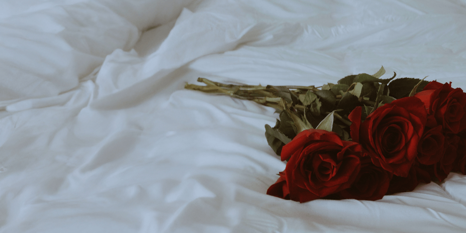 A romantic bouquet of red roses on a bed.