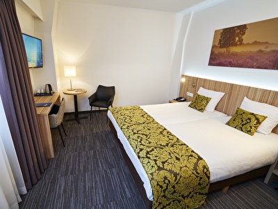 A comfortable hotel room with a bed, a desk and a television for a pleasant stay.